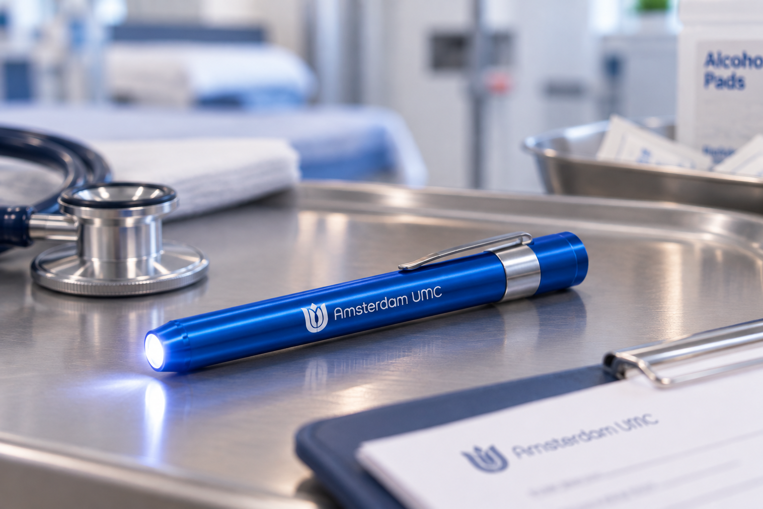 A blue medical penlight for healthcare workers, featuring a bright LED beam and a clip, resting on a stainless steel clinical tray.