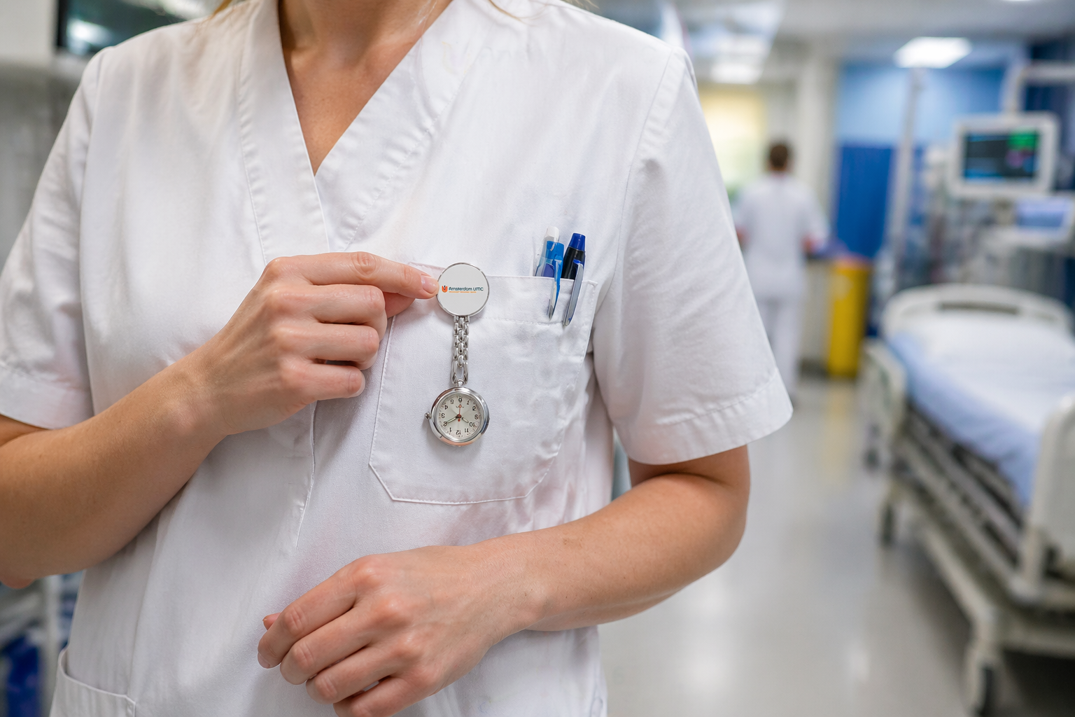 Montre gousset d'infirmière argentée fixée à un uniforme blanc, idéale pour les professionnels de santé pendant les quarts de travail.