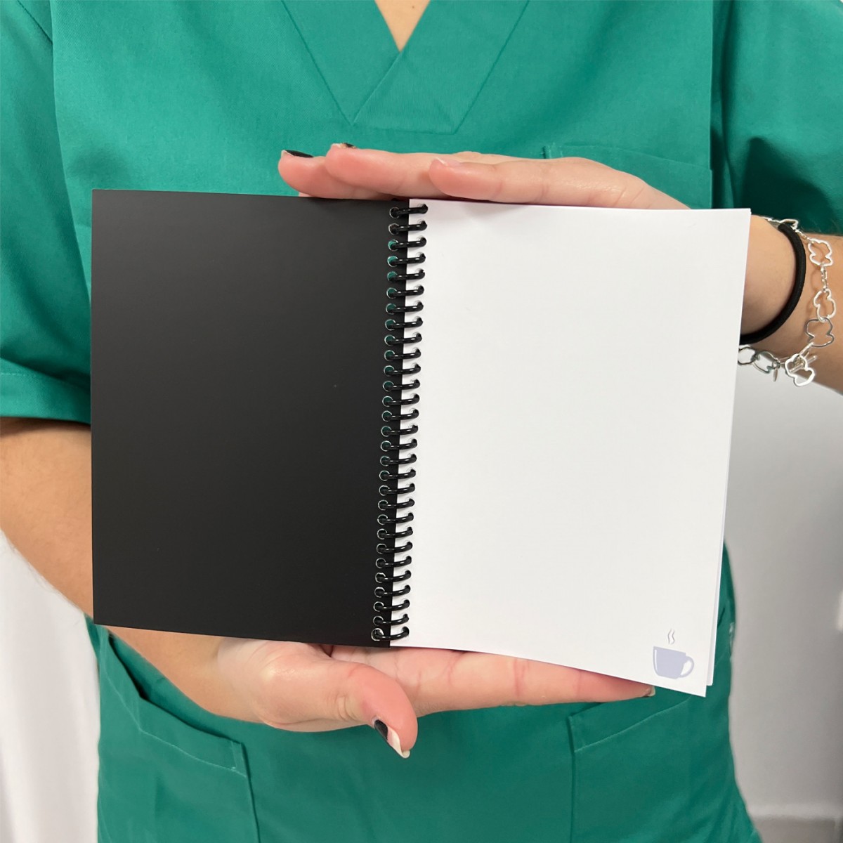 Spiralnotizbuch mit schwarzen und weißen Seiten, ideal für Krankenschwestern, um während der Schichten Notizen zu machen.